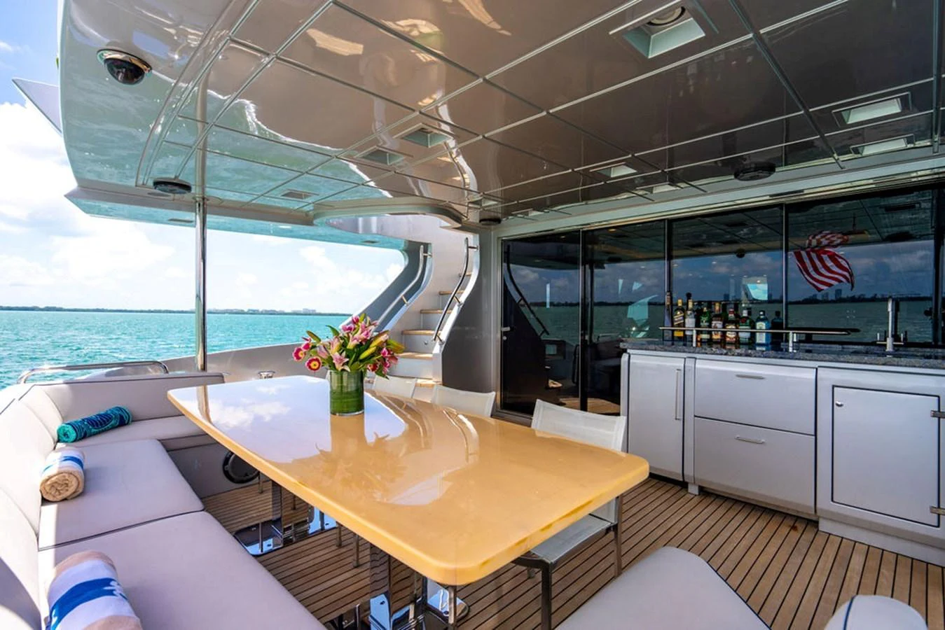 The aft deck features a comfortable seating area with a dining table and a well-equipped bar, perfect for outdoor relaxation and entertainment. aboard BEAUTIFUL M Yacht for Sale