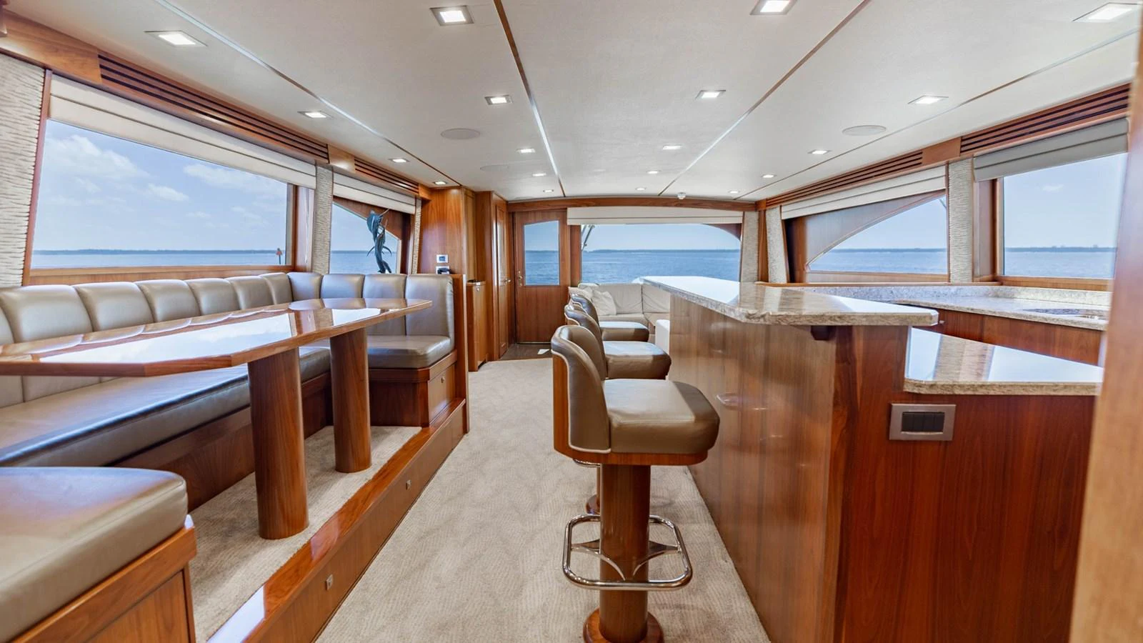 The yacht's salon features plush seating, a dining area, and a well-appointed bar with panoramic windows offering stunning sea views. aboard CE Yacht for Sale