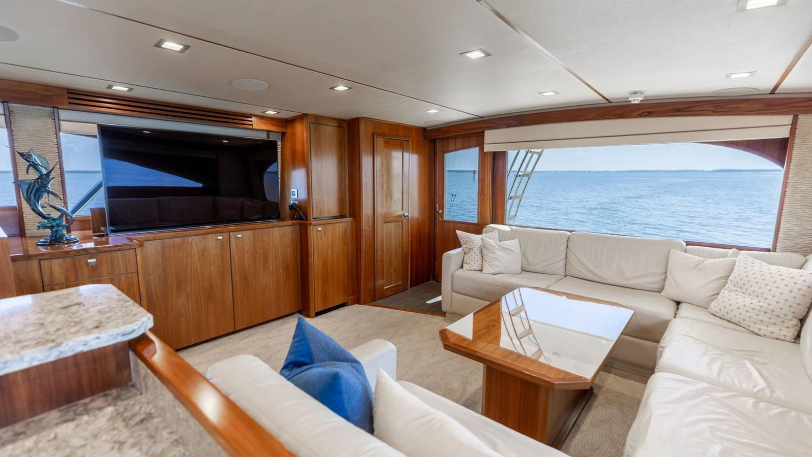 The spacious salon features elegant wood finishes and plush seating with a stunning ocean view. aboard CE Yacht for Sale