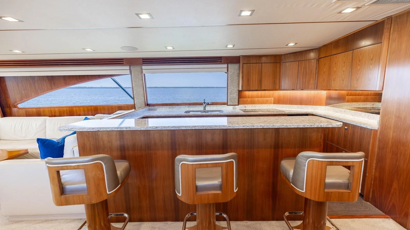 The yacht's galley features a sleek countertop with modern bar stools and ample wooden cabinetry. aboard CE Yacht for Sale