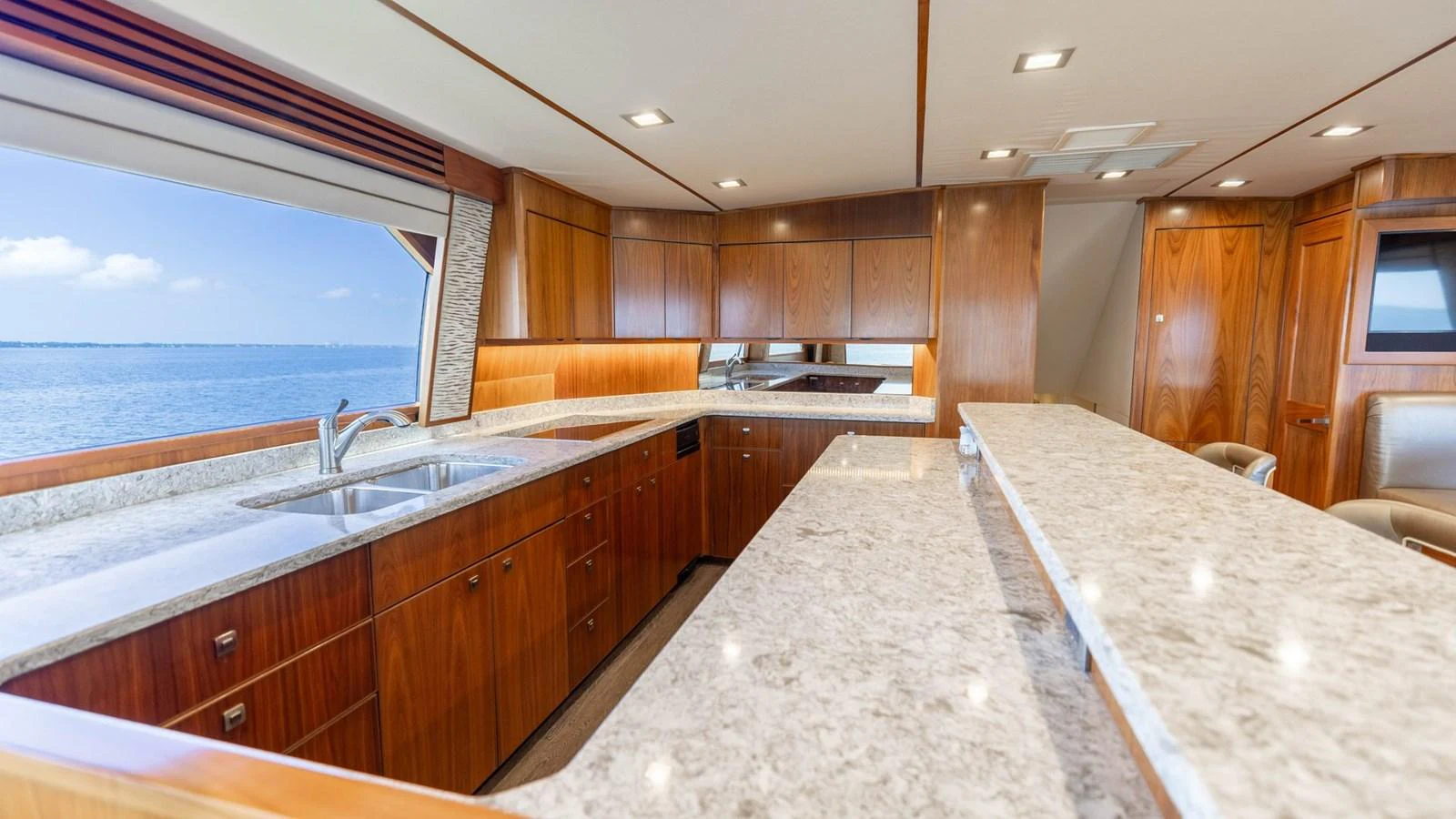 The yacht's galley features elegant wooden cabinetry and a spacious countertop with a scenic ocean view. aboard CE Yacht for Sale