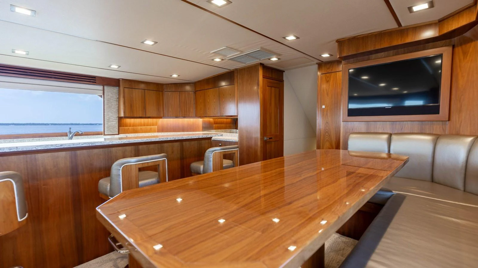 The yacht's dining area features a sleek wooden table and comfortable seating, complemented by a modern entertainment system. aboard CE Yacht for Sale