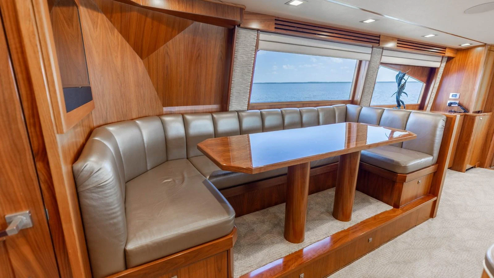 The yacht's dining area features a polished wooden table surrounded by plush leather seating, offering a comfortable and elegant space for meals with a view of the sea. aboard CE Yacht for Sale