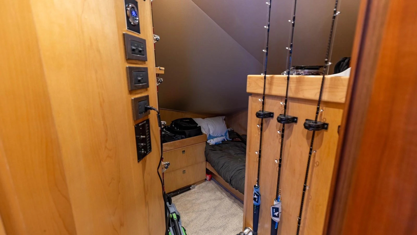 A cozy interior space with fishing rods neatly stored and a small sleeping area. aboard CE Yacht for Sale