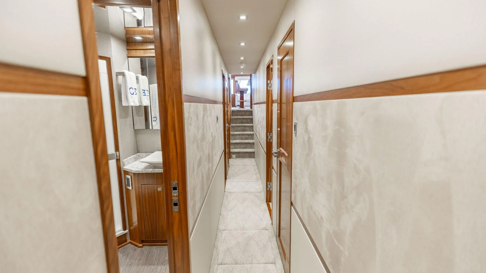 A well-lit hallway with wooden accents and multiple doors leading to different areas of the yacht. aboard CE Yacht for Sale