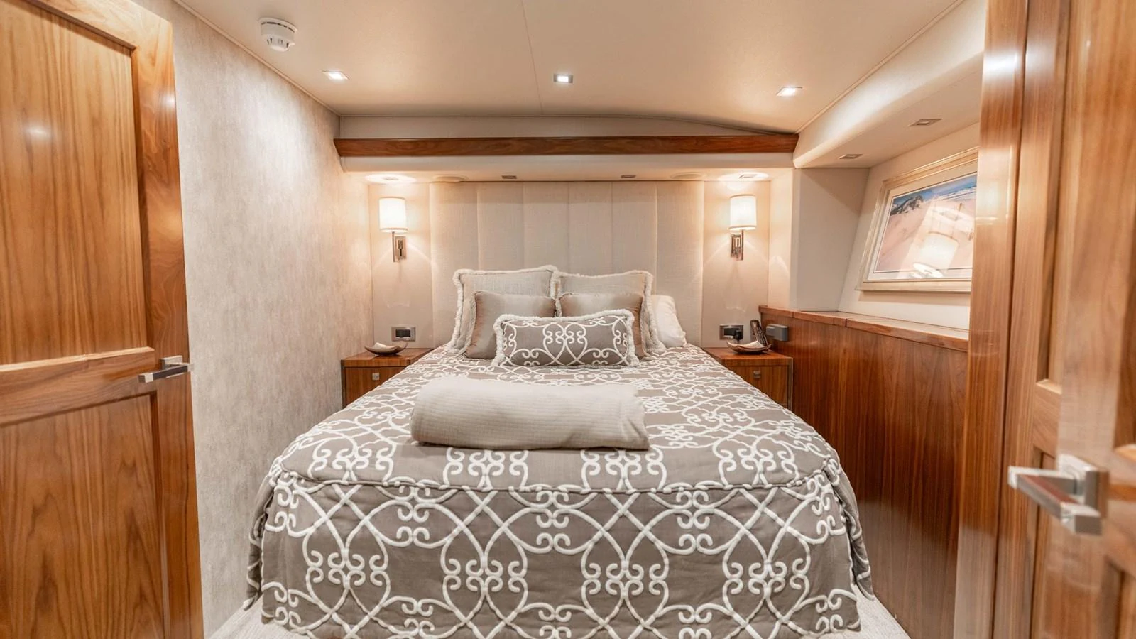 The stateroom features a plush bed with elegant bedding and warm wooden accents. aboard CE Yacht for Sale