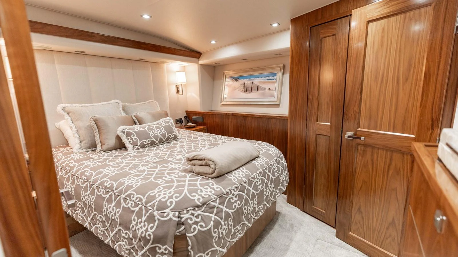 The stateroom features a cozy bed with elegant bedding and warm wooden accents. aboard CE Yacht for Sale