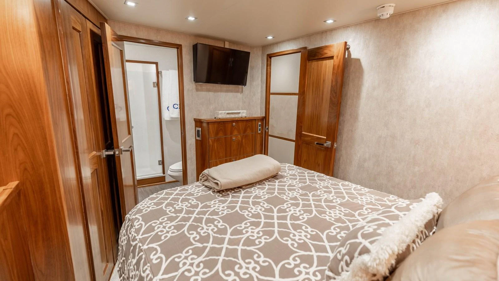 The stateroom features a cozy bed with elegant bedding and wooden accents, creating a warm and inviting atmosphere. aboard CE Yacht for Sale