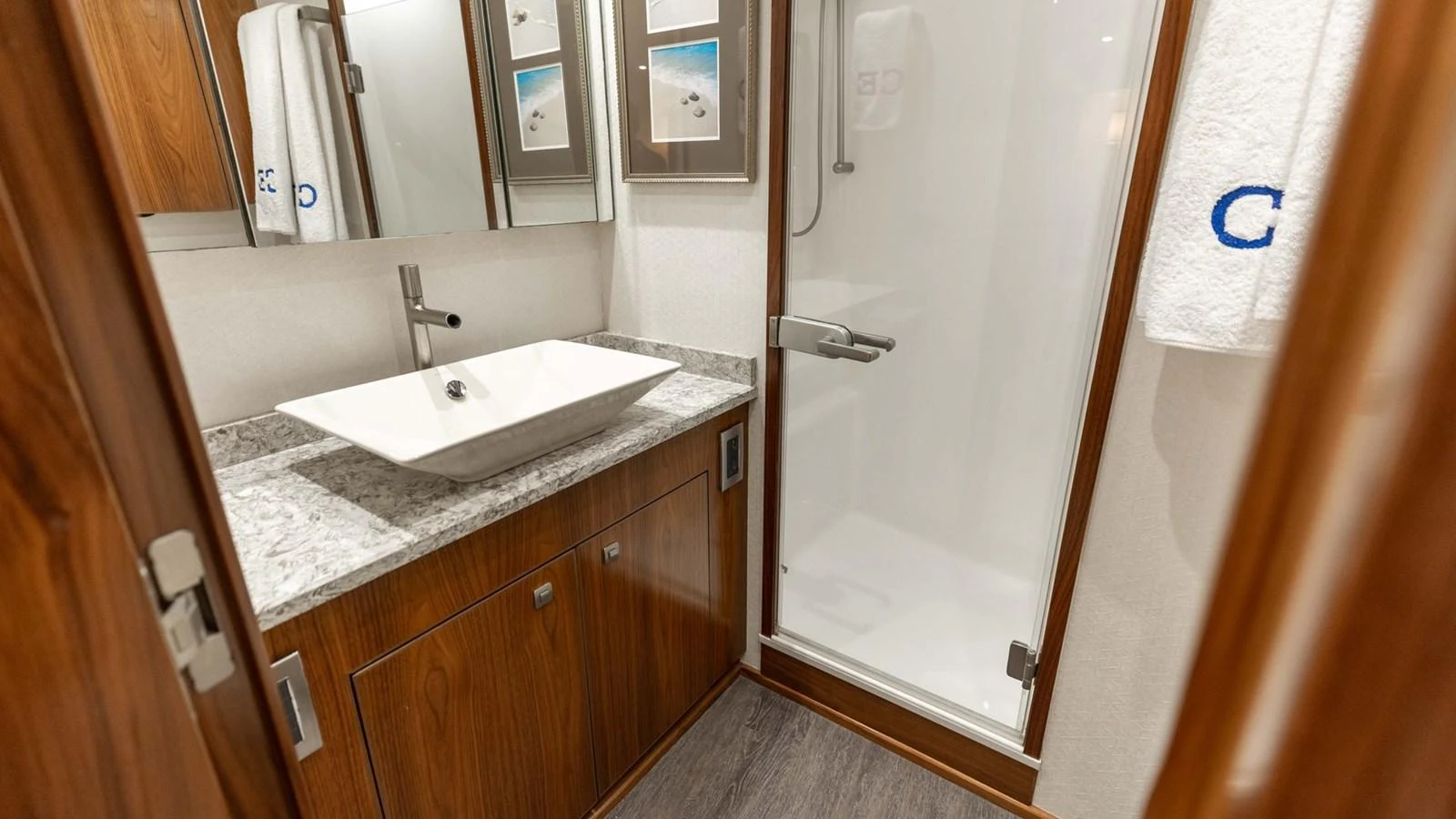 The yacht's bathroom features a modern sink and a spacious shower area with elegant wooden cabinetry. aboard CE Yacht for Sale