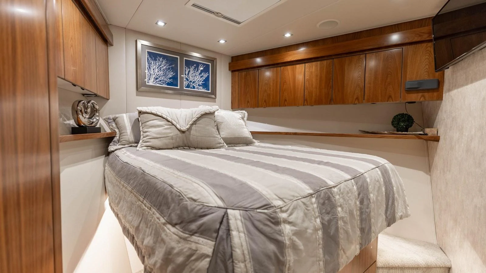 The stateroom features a cozy bed with elegant wood finishes and soft lighting. aboard CE Yacht for Sale