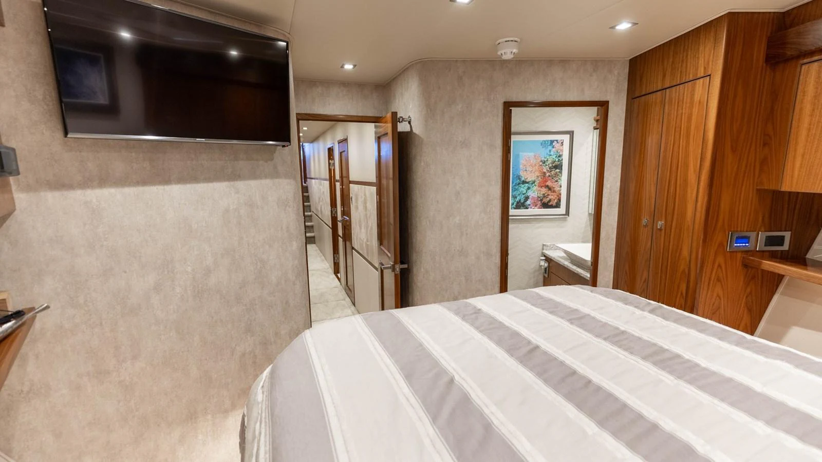 A cozy stateroom featuring a comfortable bed, wood accents, and a flat-screen TV. aboard CE Yacht for Sale