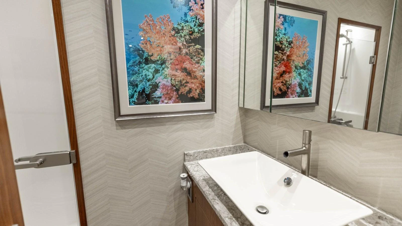 A stylish yacht bathroom featuring a modern sink and vibrant coral artwork. aboard CE Yacht for Sale