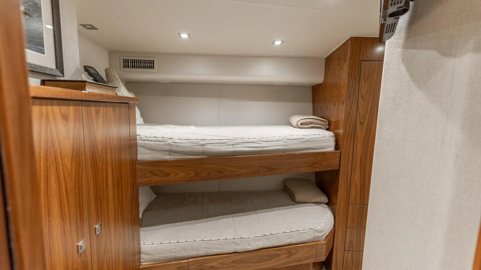 The cozy bunk room features warm wood finishes and comfortable bedding. aboard CE Yacht for Sale