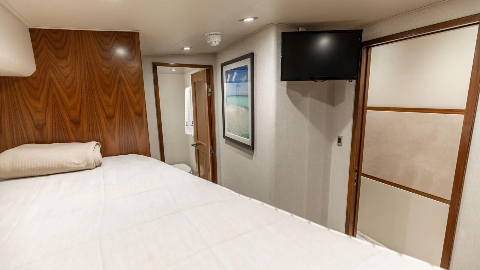 A cozy stateroom featuring a comfortable bed, wood paneling, and modern amenities. aboard CE Yacht for Sale