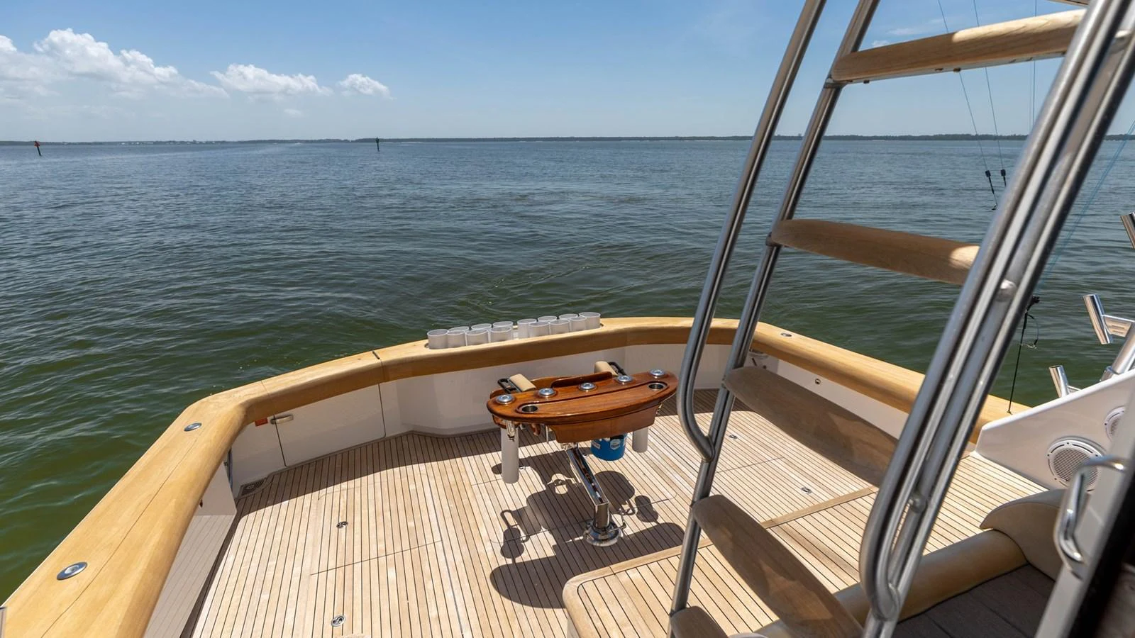 The aft deck features a spacious area with wooden flooring and a fishing chair, perfect for leisurely activities. aboard CE Yacht for Sale