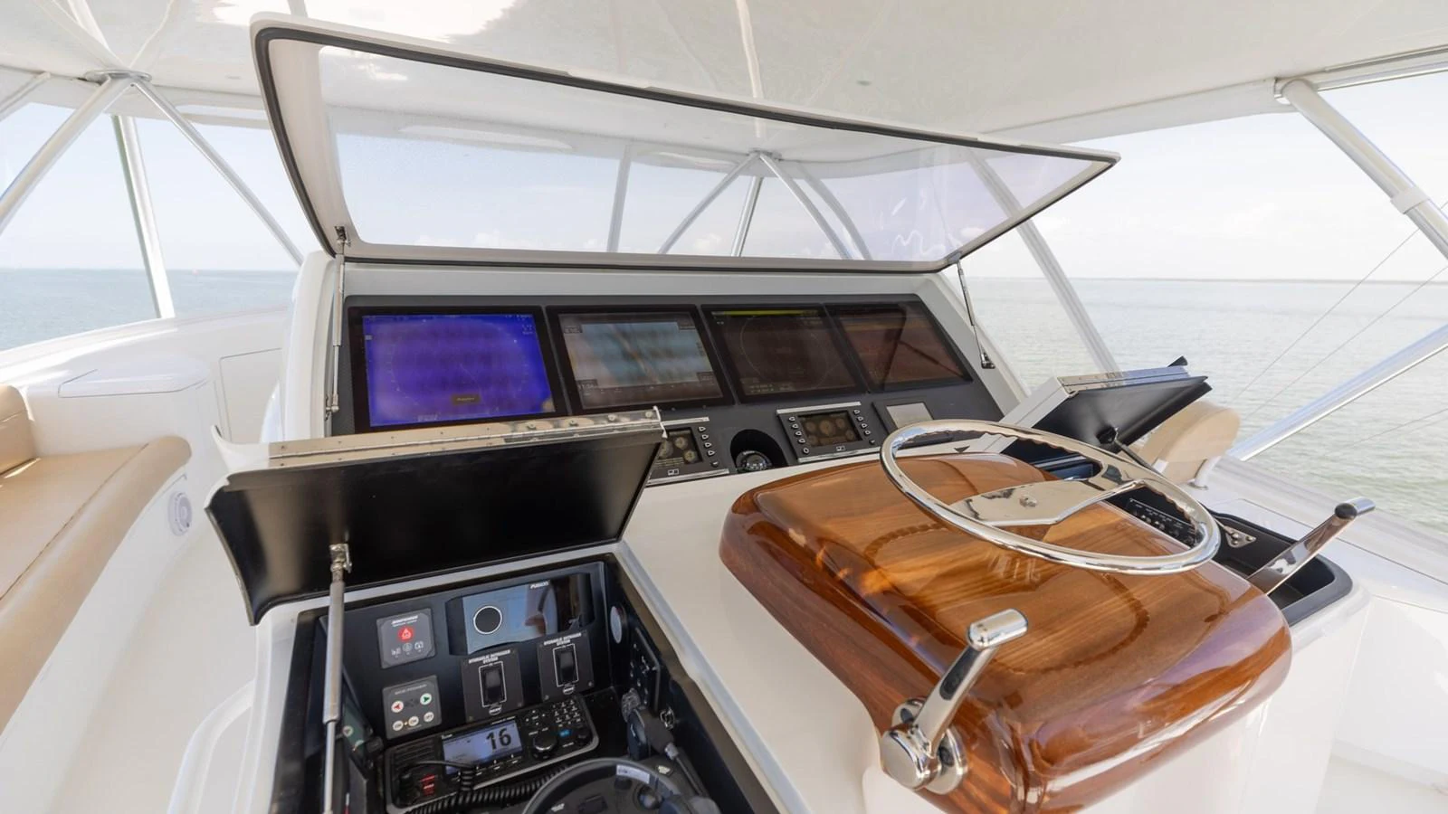 The helm station features advanced navigation equipment and a polished wooden steering wheel. aboard CE Yacht for Sale
