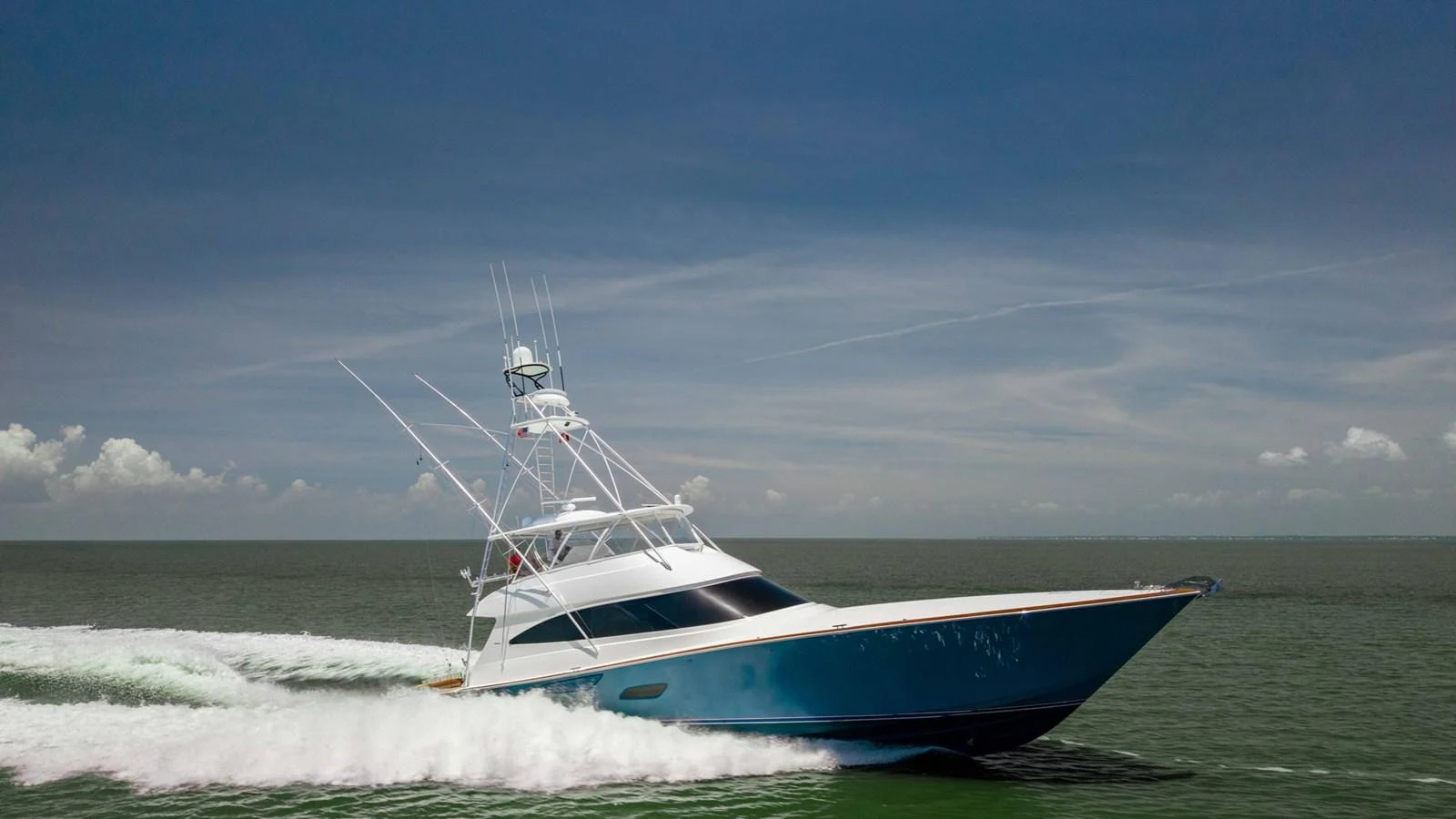 A sleek yacht glides swiftly across the water under a clear blue sky. aboard CE Yacht for Sale