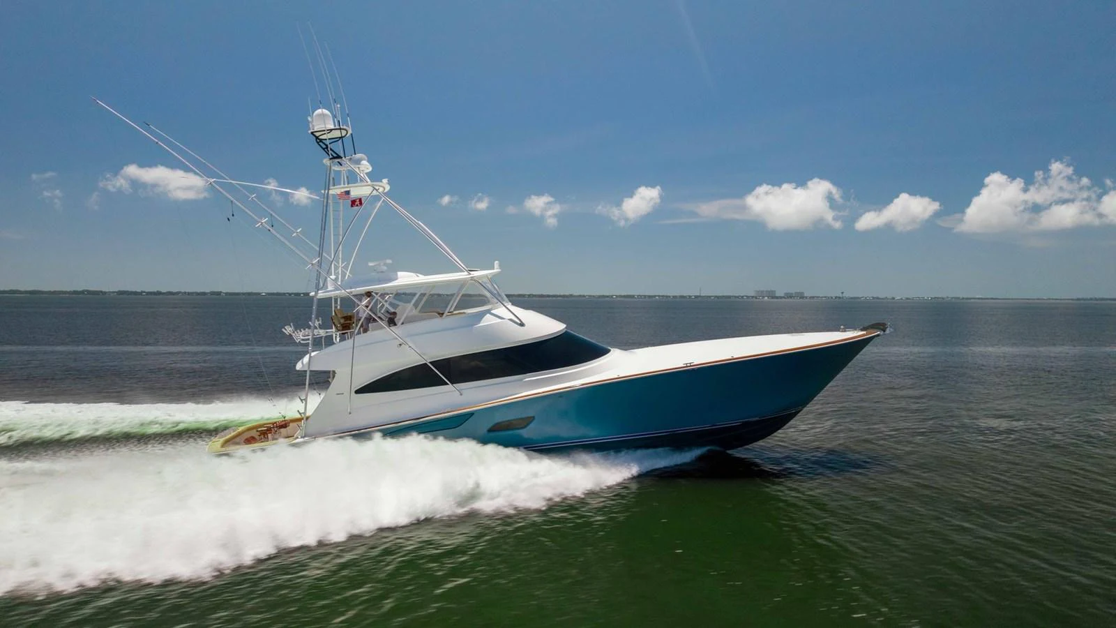 A sleek yacht cruises swiftly across calm waters under a clear blue sky. aboard CE Yacht for Sale