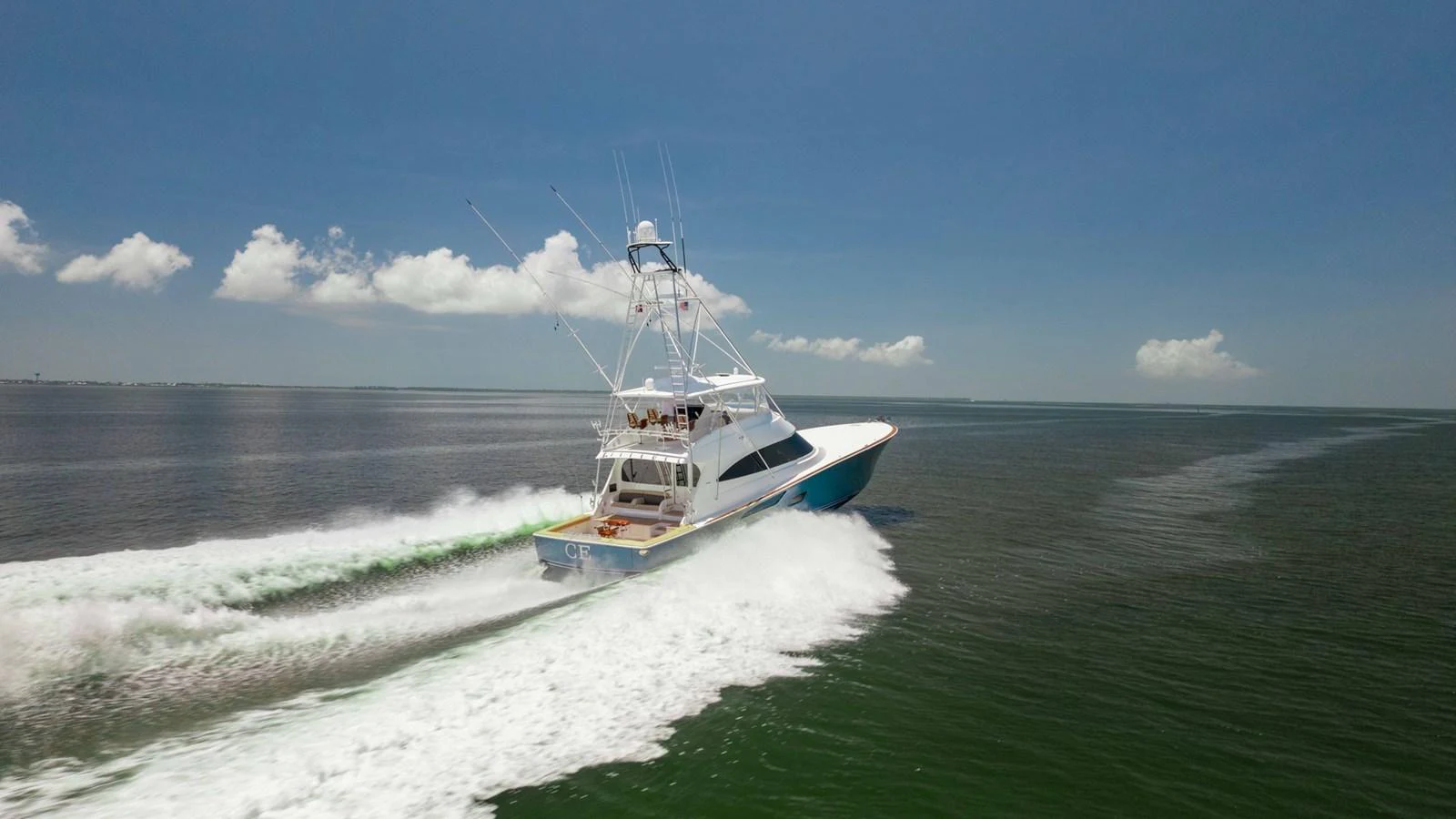 A sleek yacht speeds across the open water, leaving a trail of white foam behind. aboard CE Yacht for Sale