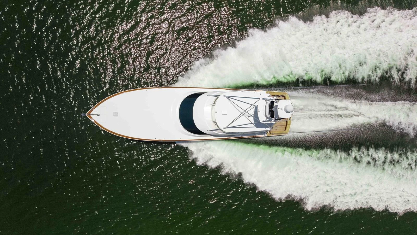 A sleek yacht glides swiftly through the water, leaving a trail of white wake behind. aboard CE Yacht for Sale