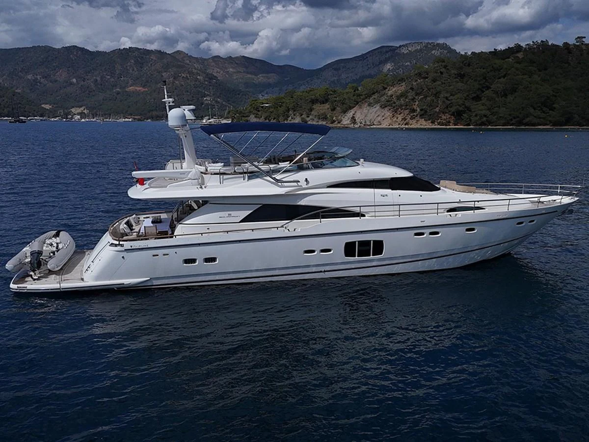 A sleek and elegant yacht cruising on calm waters with scenic mountains in the background. aboard SEDEF Yacht for Sale