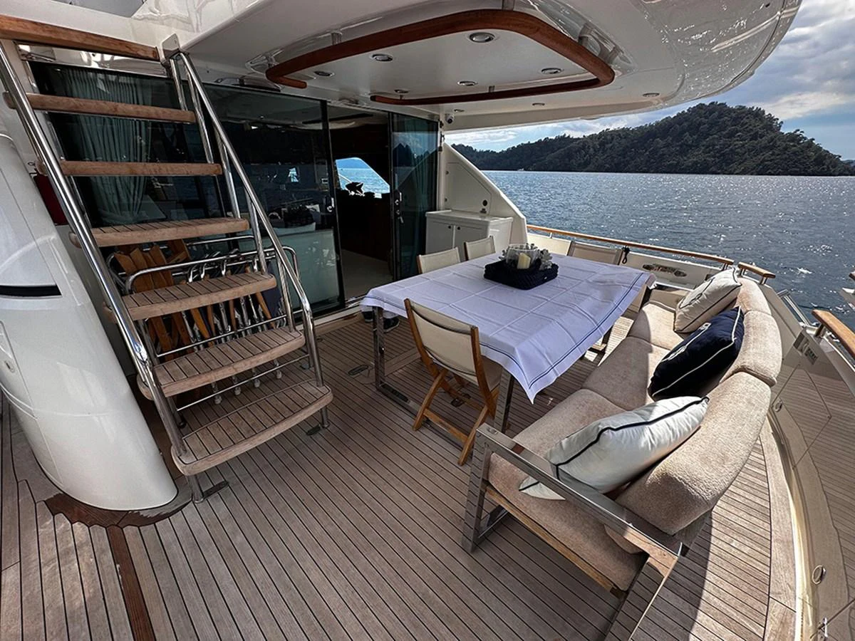 The aft deck features a stylish dining area with a table set for an alfresco meal, surrounded by comfortable seating and a scenic view of the water. aboard SEDEF Yacht for Sale
