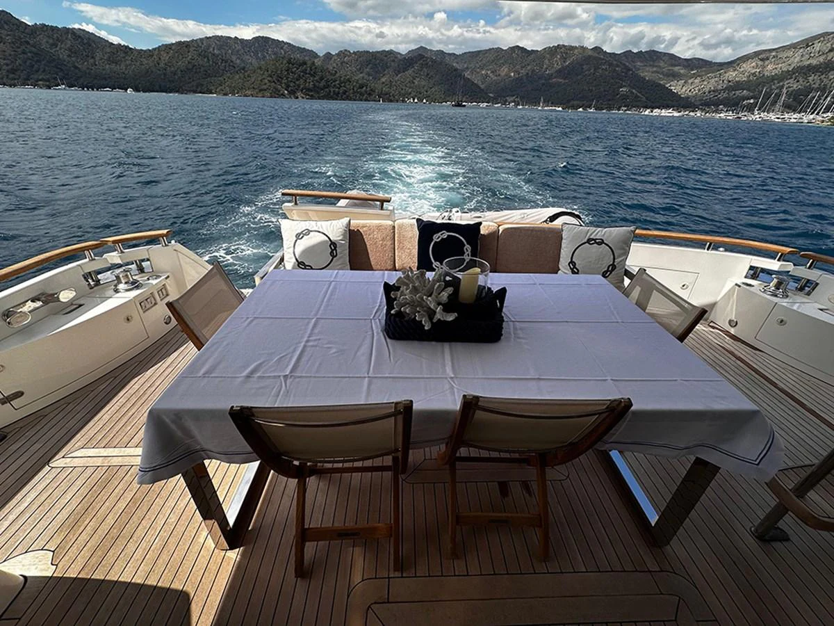 The aft deck features a stylish dining area with a scenic view of the sea and mountains. aboard SEDEF Yacht for Sale