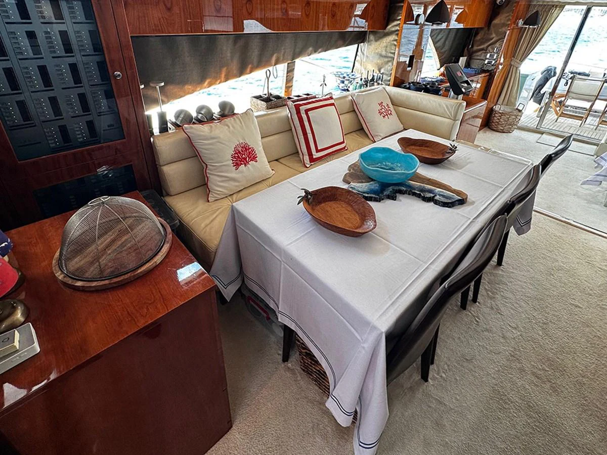 A cozy dining area with a table set for a meal, adjacent to a comfortable seating area with decorative pillows. aboard SEDEF Yacht for Sale