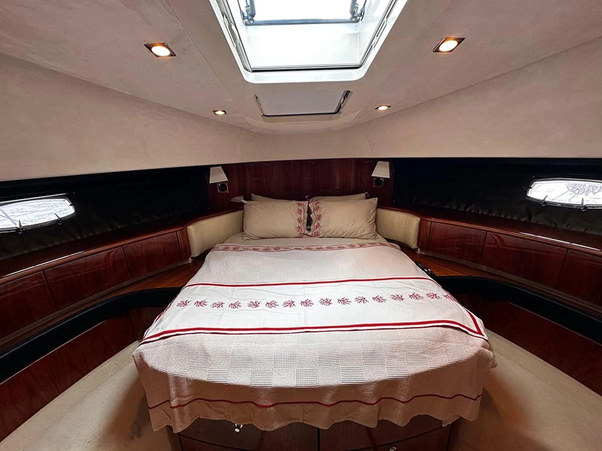The stateroom features a cozy bed with elegant bedding and ample natural light from the overhead skylight. aboard SEDEF Yacht for Sale