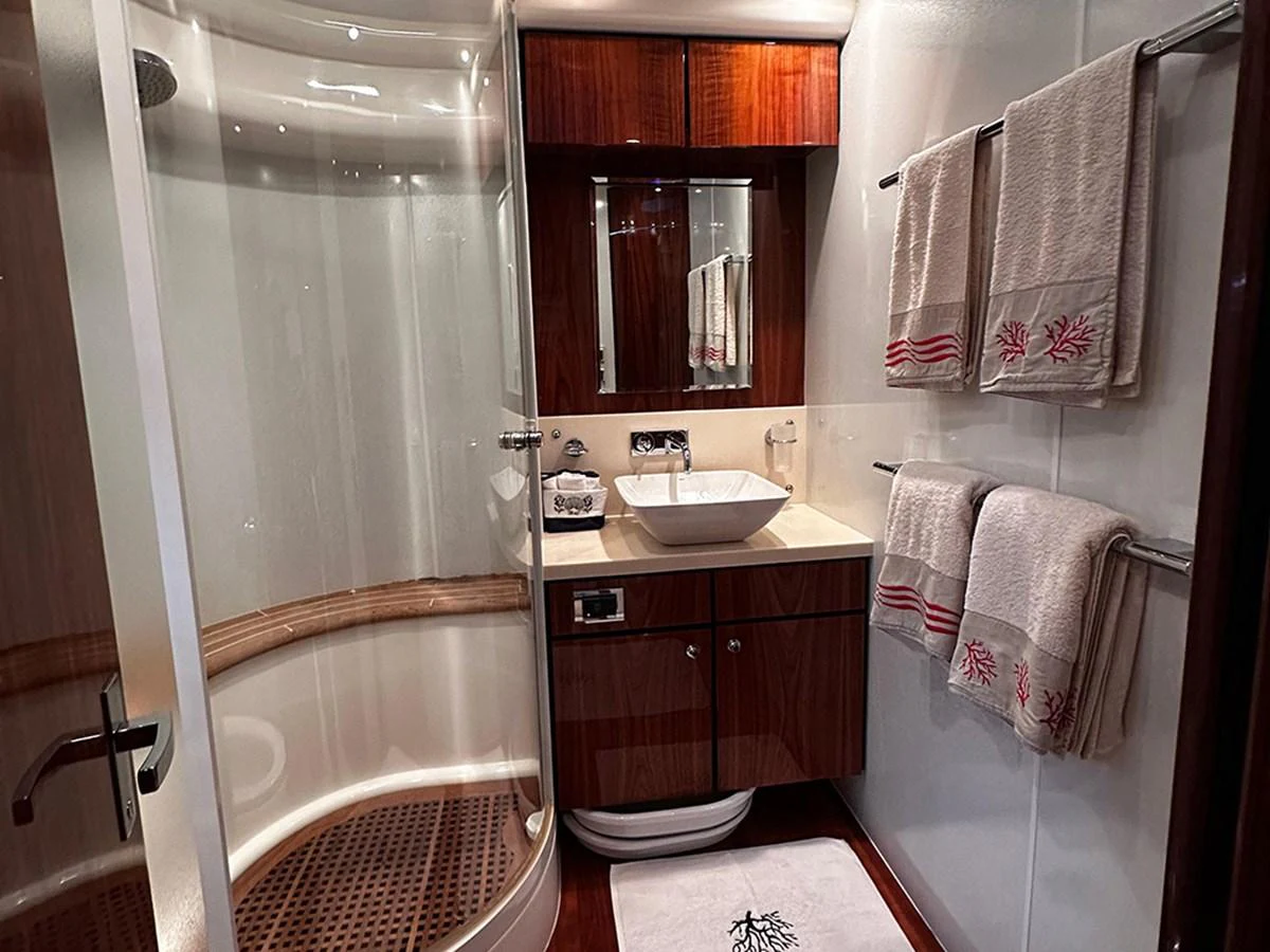 The yacht's bathroom features a modern shower, elegant wooden cabinetry, and plush towels. aboard SEDEF Yacht for Sale