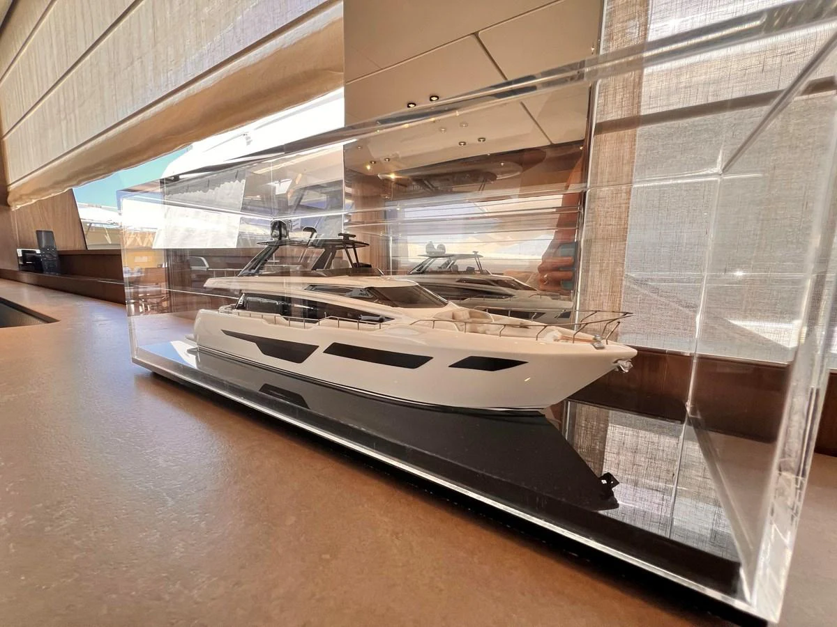 A detailed model of a yacht is displayed in a glass case, showcasing its sleek design. aboard LD Yacht for Sale