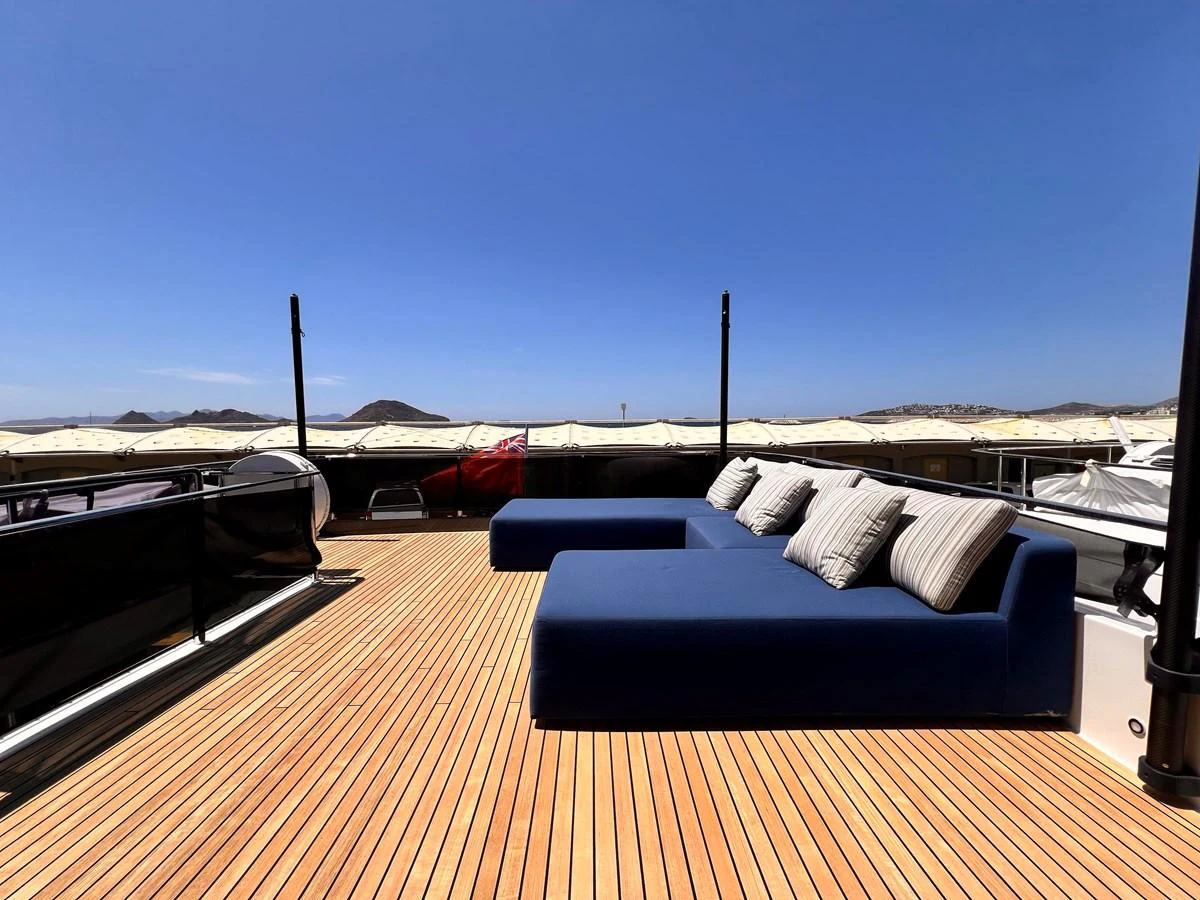 The sundeck features a spacious lounging area with plush blue seating and a scenic view. aboard LD Yacht for Sale