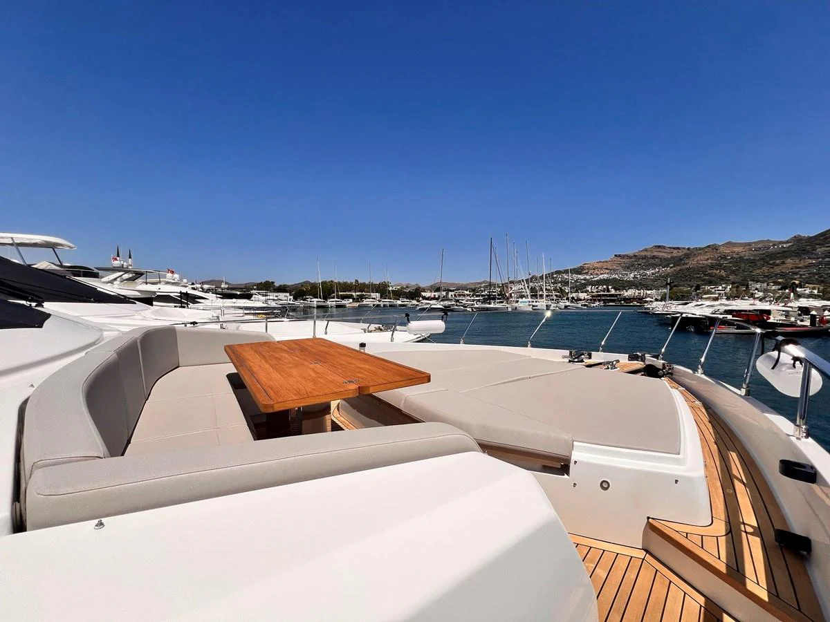 The yacht's foredeck features a spacious seating area with a wooden table, perfect for enjoying the view. aboard LD Yacht for Sale