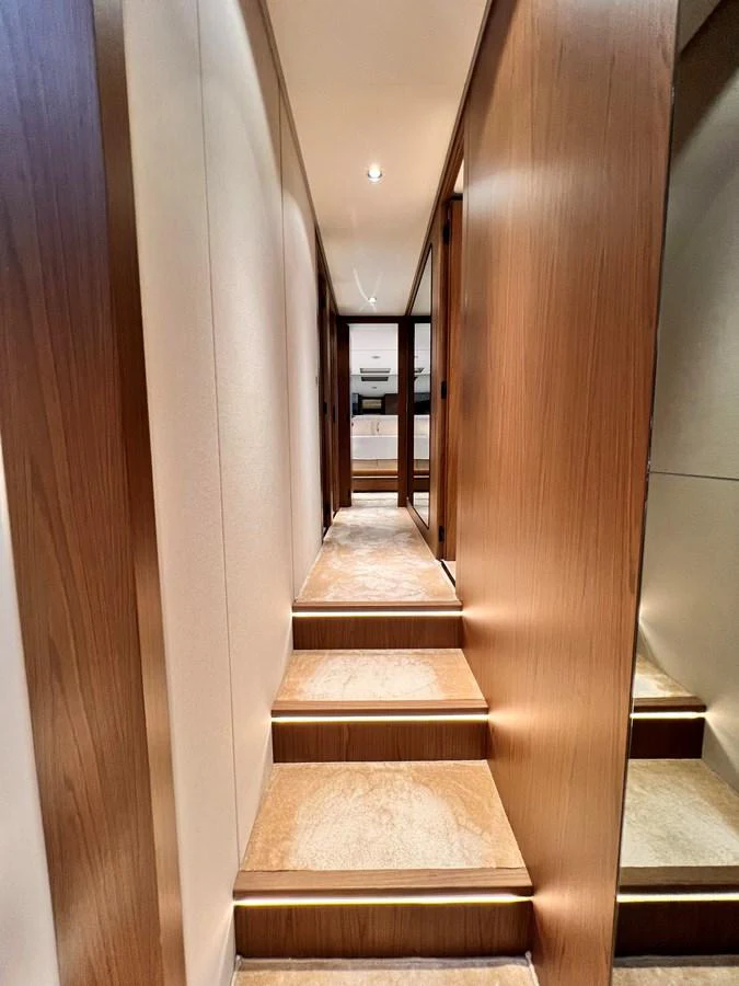 A narrow hallway with wooden paneling and carpeted steps leads to another section of the yacht. aboard LD Yacht for Sale