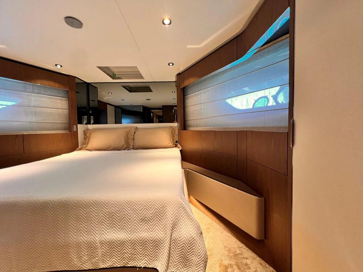 The stateroom features a luxurious bed with elegant wood paneling and soft lighting. aboard LD Yacht for Sale