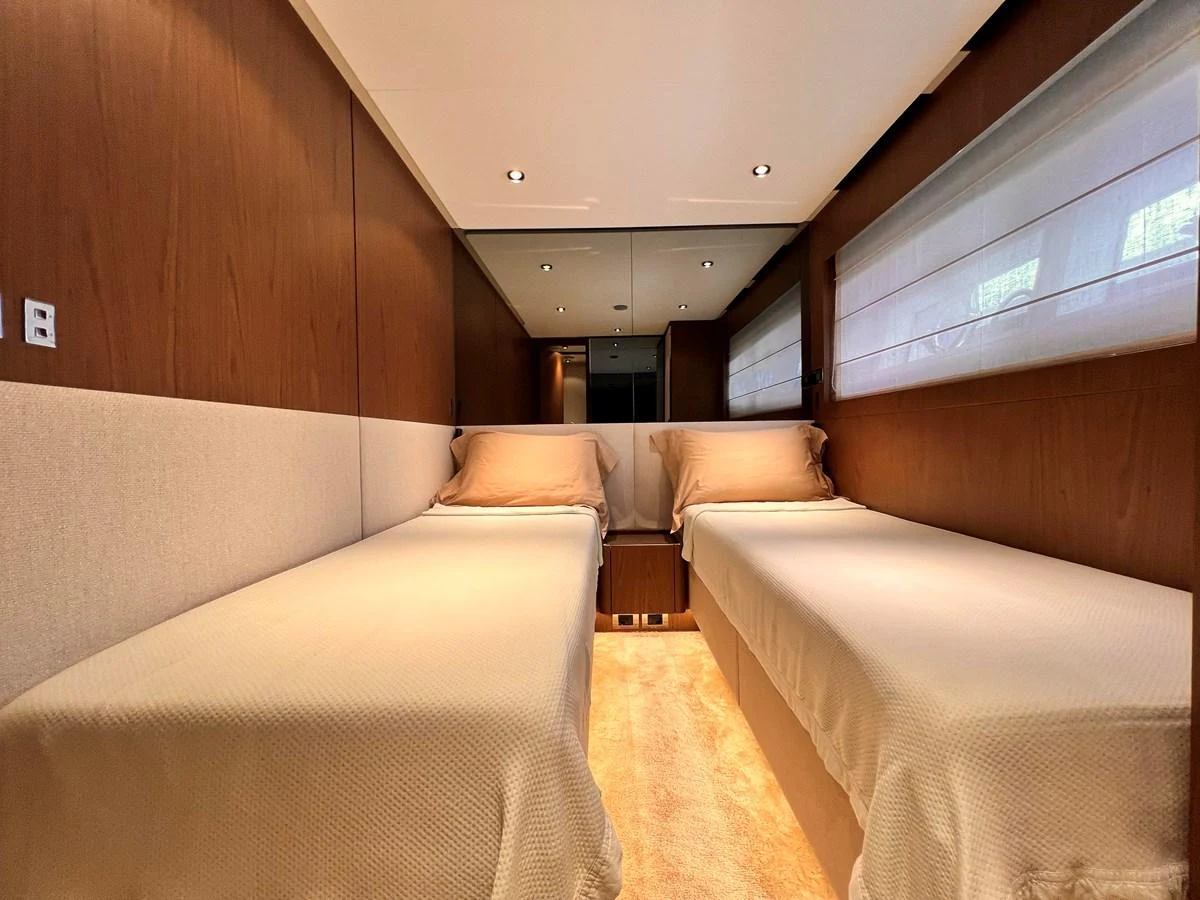 The twin stateroom features two single beds with elegant bedding and warm wooden accents. aboard LD Yacht for Sale