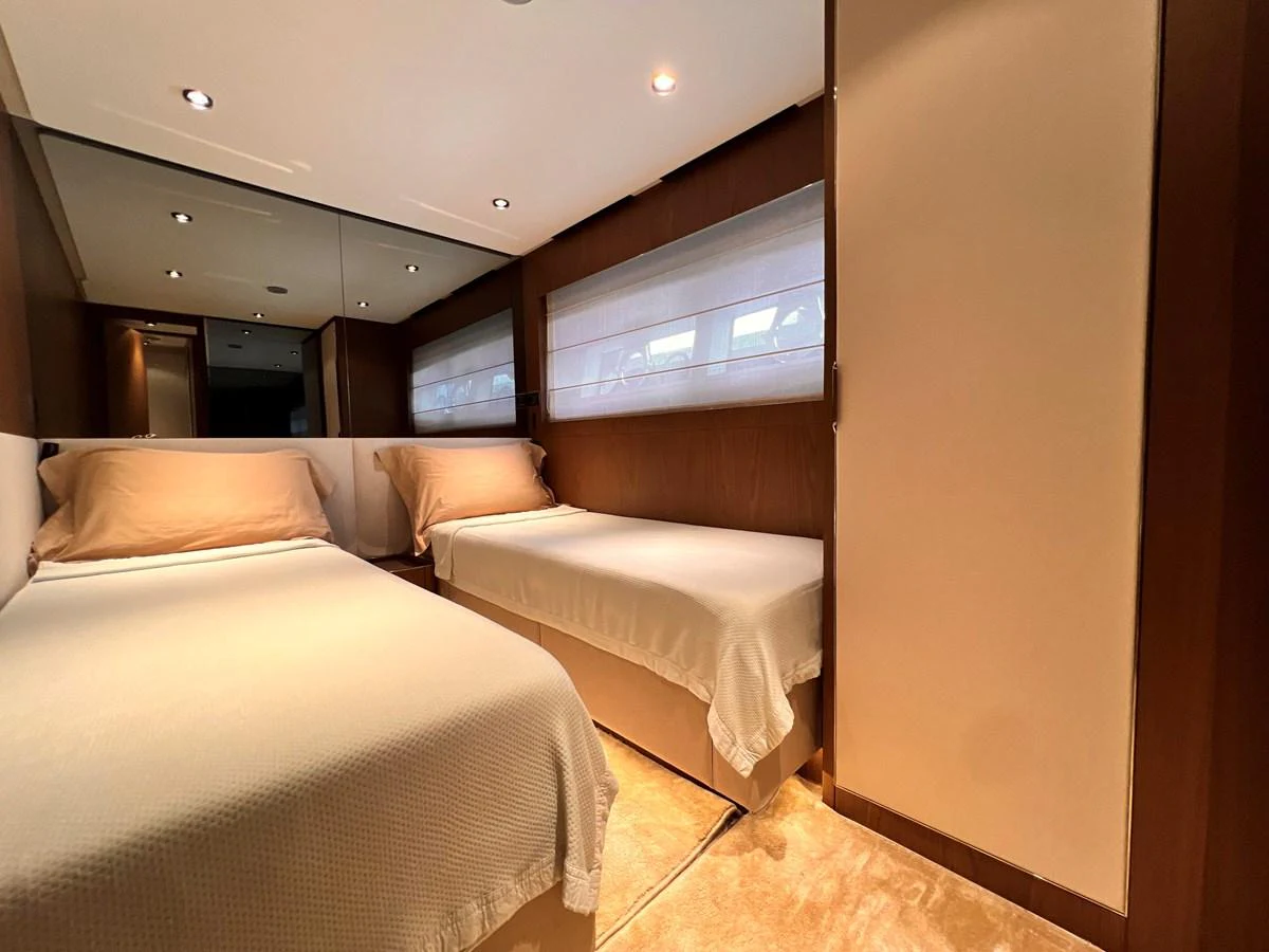 The twin stateroom features two single beds with elegant bedding and warm lighting. aboard LD Yacht for Sale