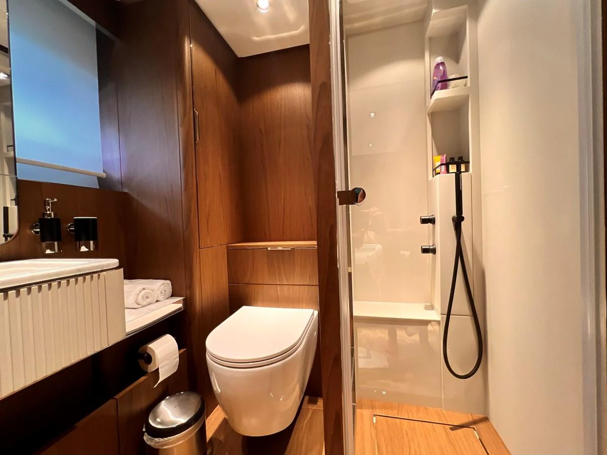 A modern yacht bathroom featuring a sleek design with wooden accents and a glass-enclosed shower. aboard LD Yacht for Sale