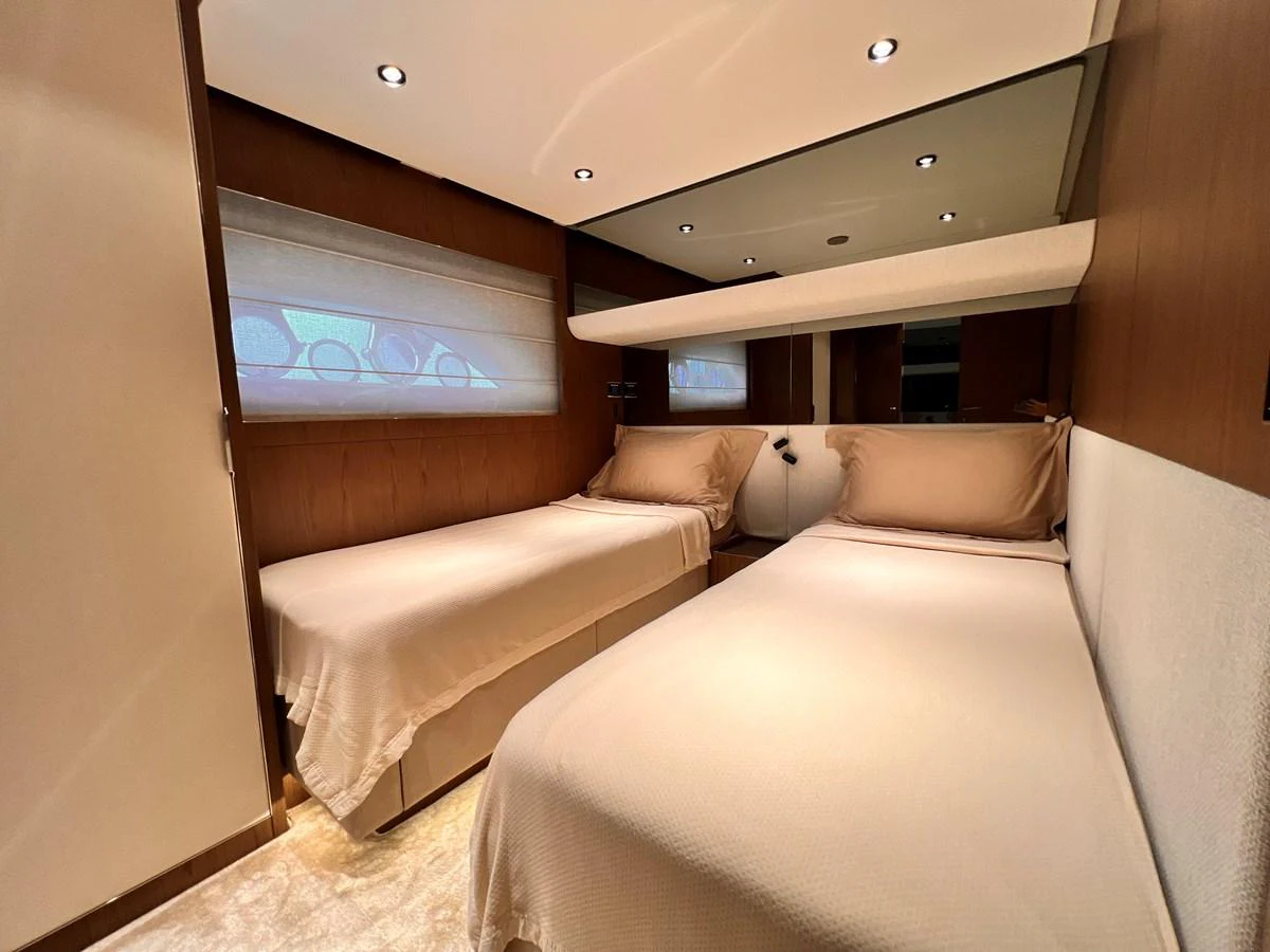 The guest stateroom features twin beds with elegant bedding and warm wood paneling. aboard LD Yacht for Sale