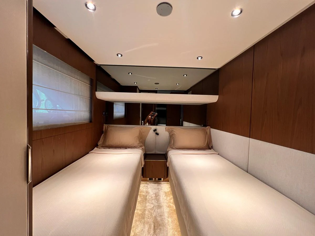 The twin stateroom features two single beds with elegant bedding and warm wood paneling. aboard LD Yacht for Sale