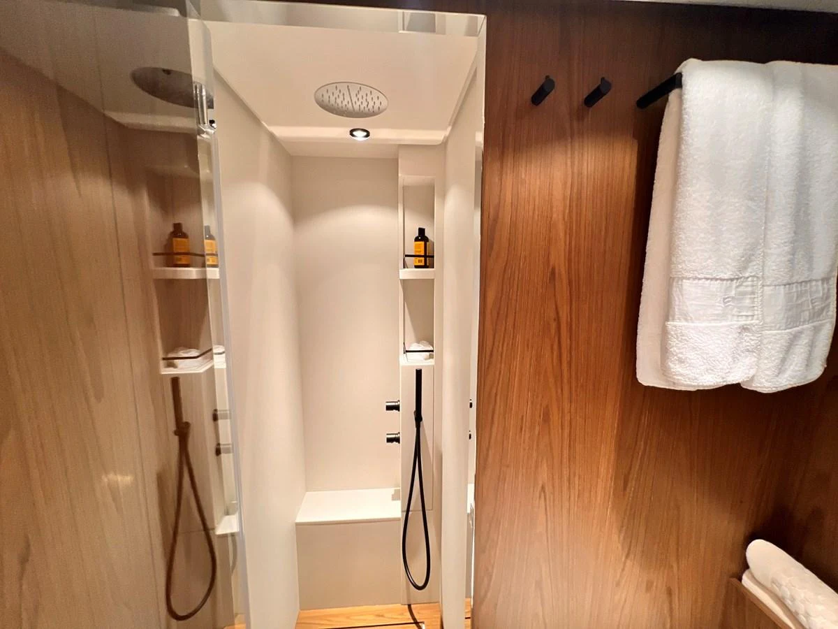 The yacht's bathroom features a sleek shower area with modern fixtures and wooden accents. aboard LD Yacht for Sale