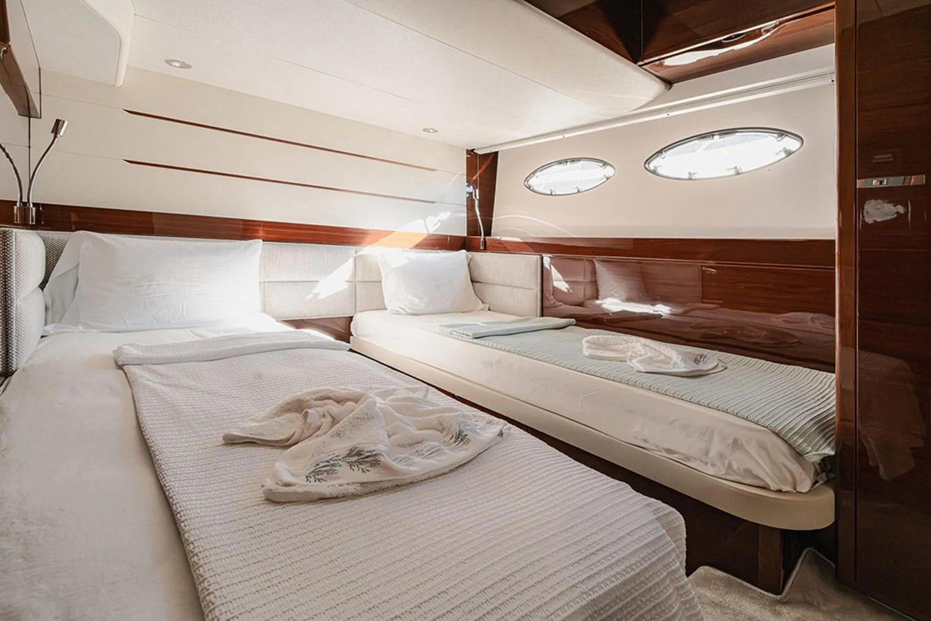 The guest stateroom features twin beds with elegant bedding and ample natural light from the portholes. aboard DAPHNE Yacht for Sale
