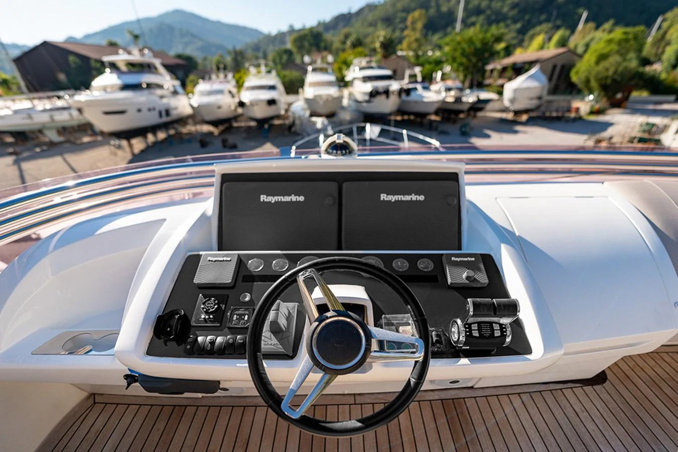 The helm station features advanced navigation equipment and a sleek steering wheel, set against a backdrop of docked yachts. aboard DAPHNE Yacht for Sale