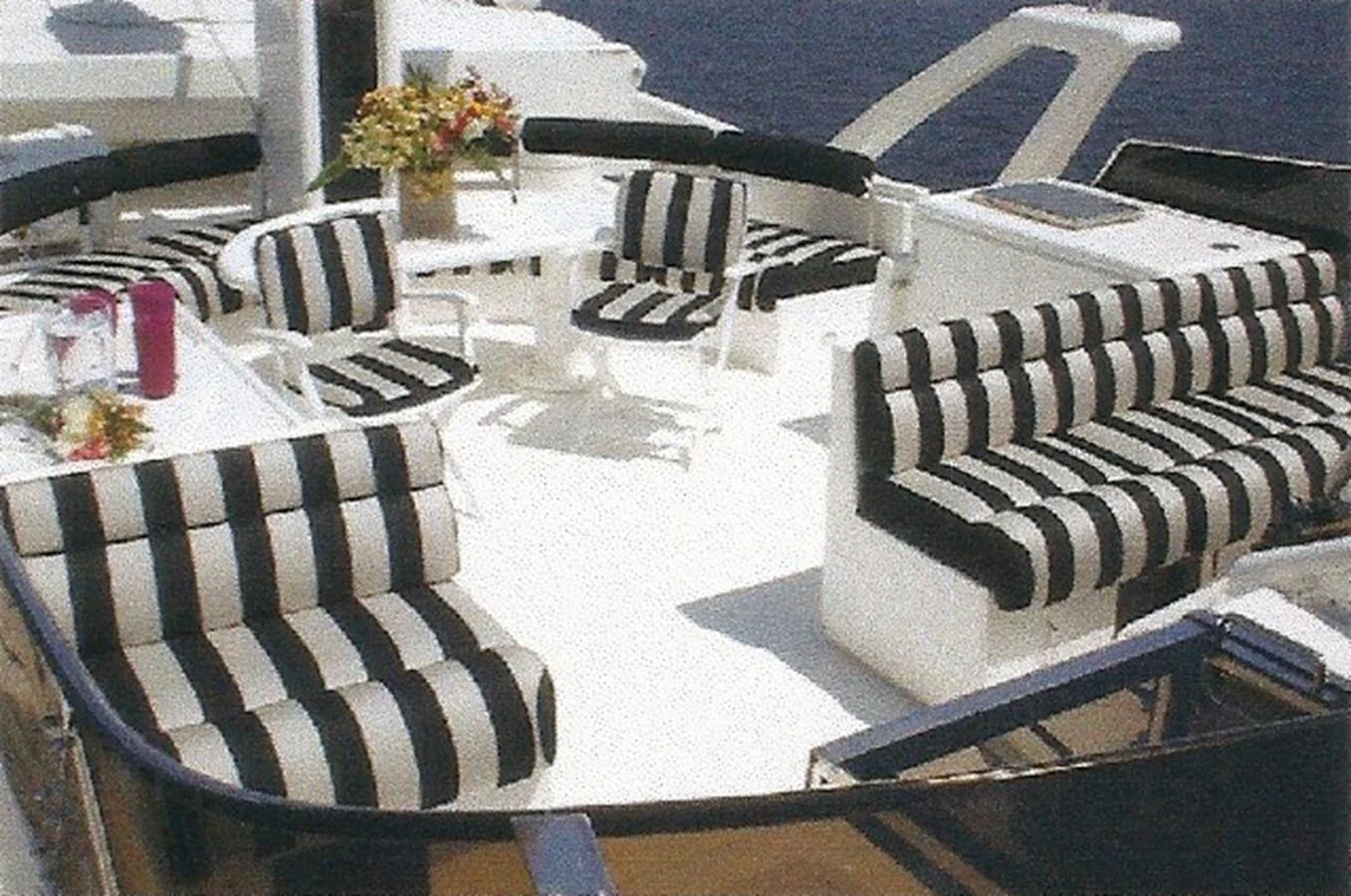 The flybridge features stylish black and white striped seating with a dining area and a view of the water. aboard SHOW ME THE MONEY Yacht for Sale