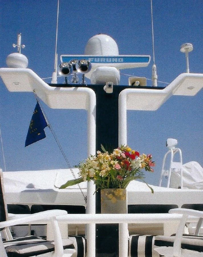 A close-up view of the yacht's radar mast adorned with a vase of flowers in the foreground. aboard SHOW ME THE MONEY Yacht for Sale