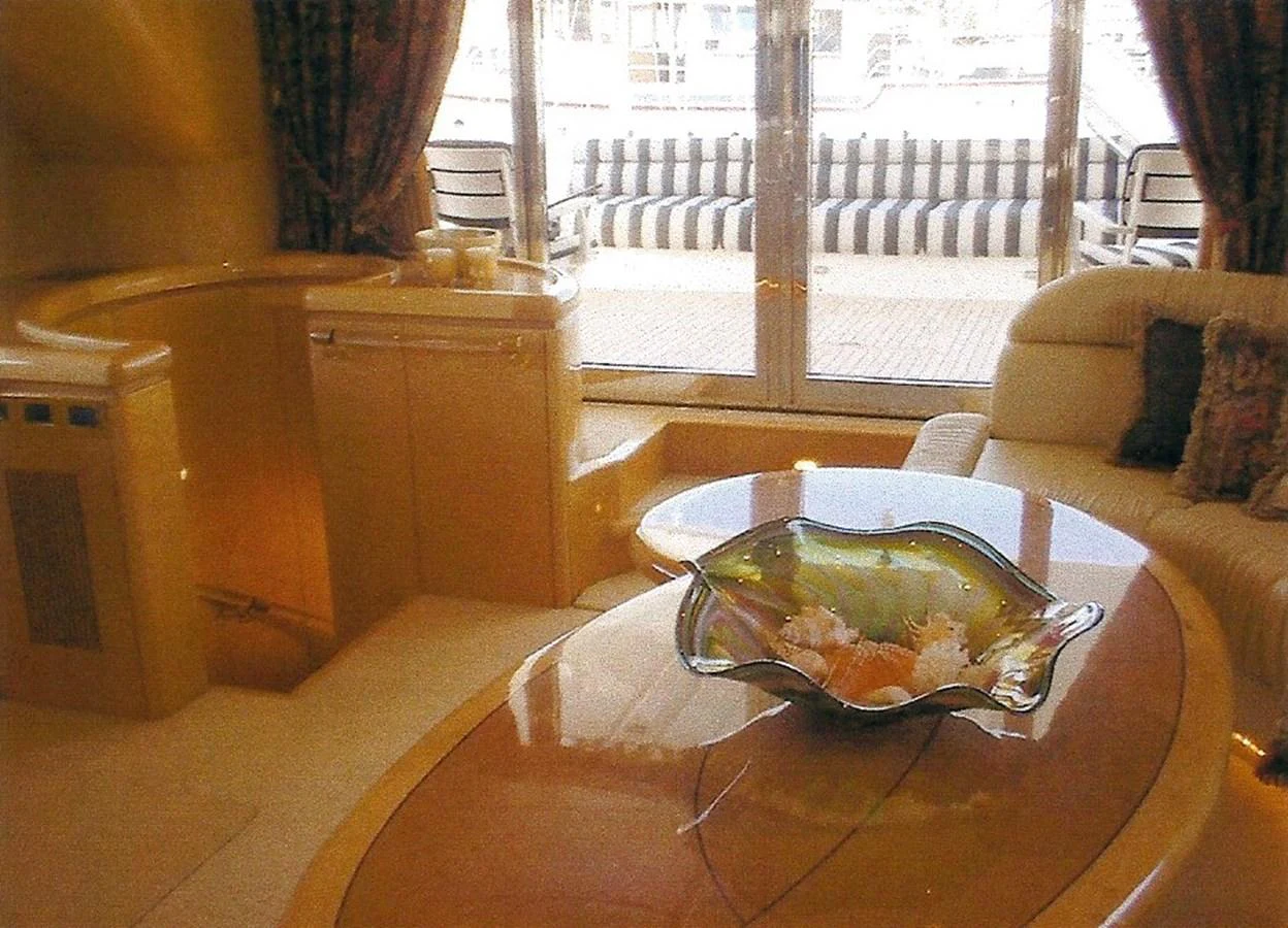 The yacht's interior features a cozy seating area with a stylish table centerpiece and large windows offering a view of the deck. aboard SHOW ME THE MONEY Yacht for Sale