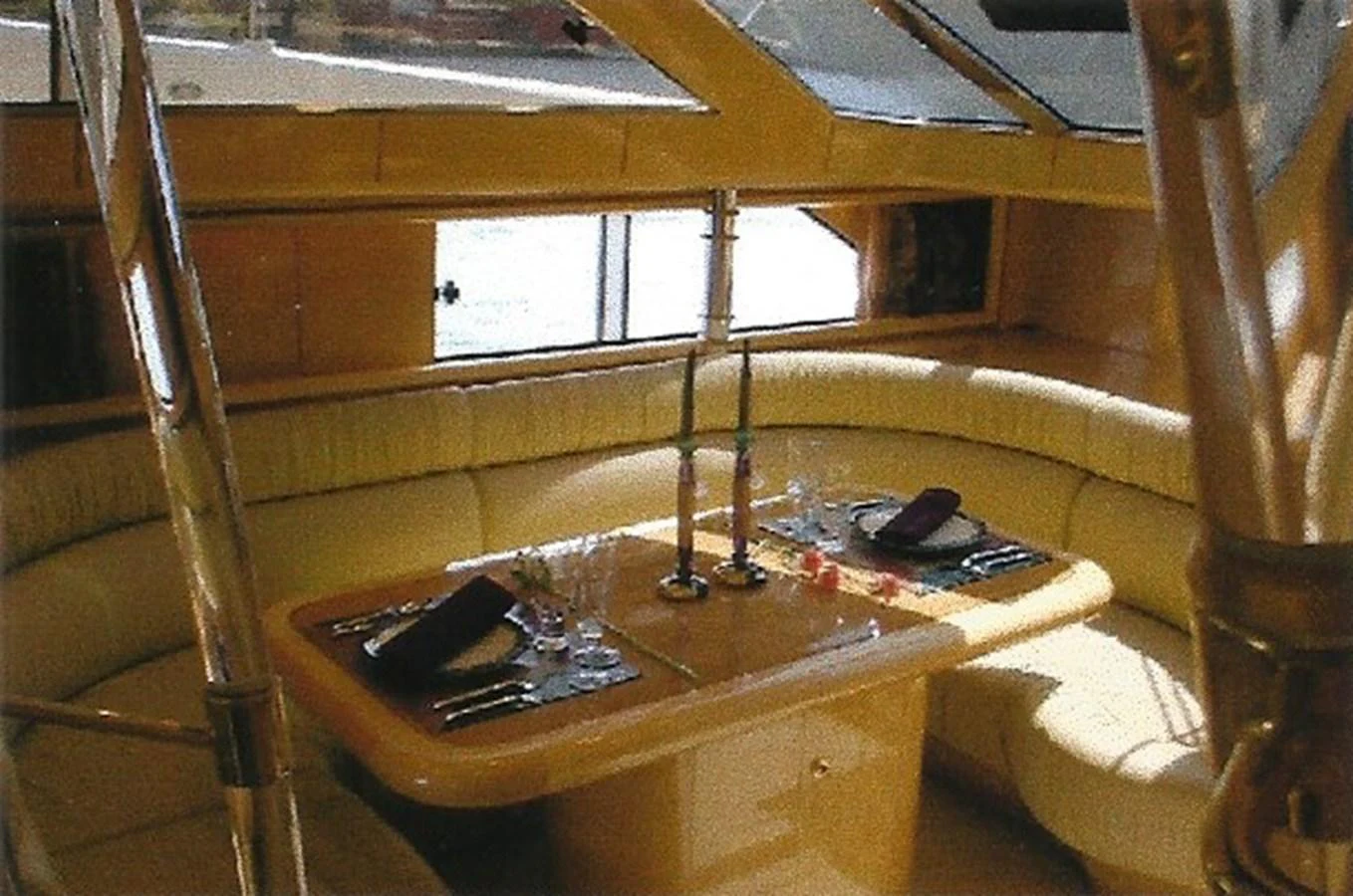 The yacht's interior dining area features a cozy, well-lit space with a curved seating arrangement and elegant table settings. aboard SHOW ME THE MONEY Yacht for Sale