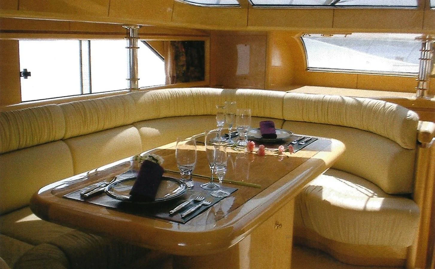 The yacht's dining area features a cozy, curved seating arrangement with a polished wooden table set for a meal. aboard SHOW ME THE MONEY Yacht for Sale