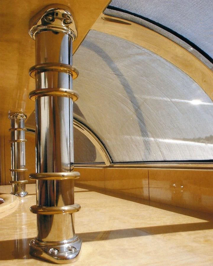 A close-up view of polished metal columns and a curved window in a luxurious yacht interior. aboard SHOW ME THE MONEY Yacht for Sale