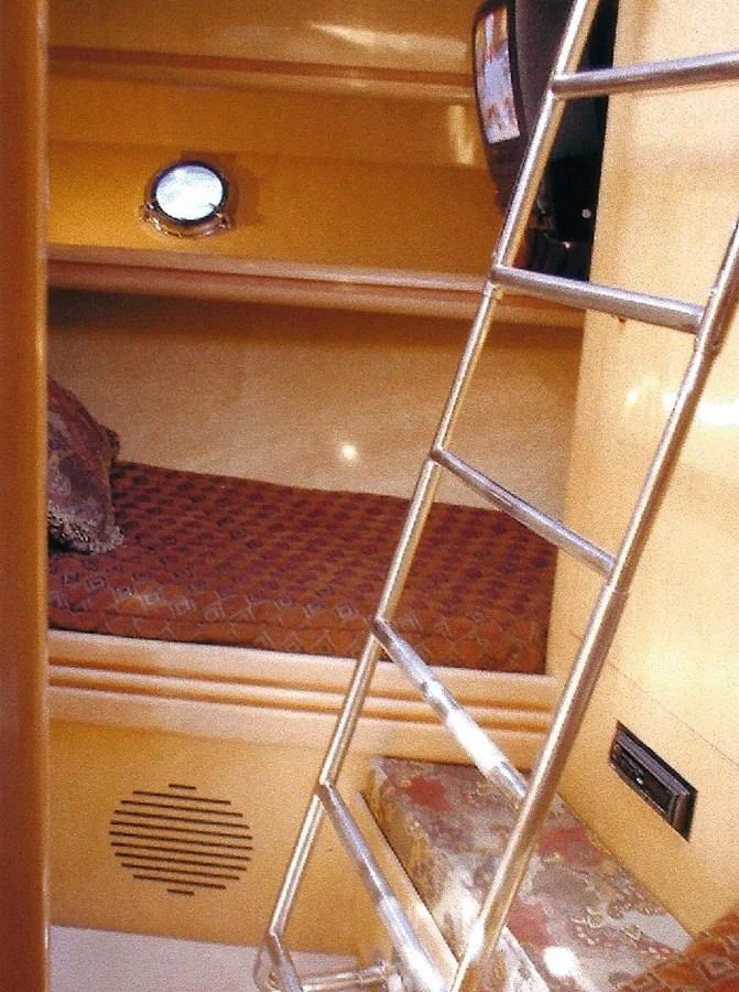 A cozy cabin with a ladder leading to a bunk bed and a small porthole. aboard SHOW ME THE MONEY Yacht for Sale
